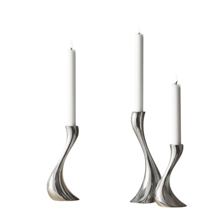 Set of three silver candle holders with candles on a white background