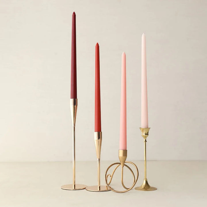 Red and pink wax taper candles in gold holders, minimalist dining table décor