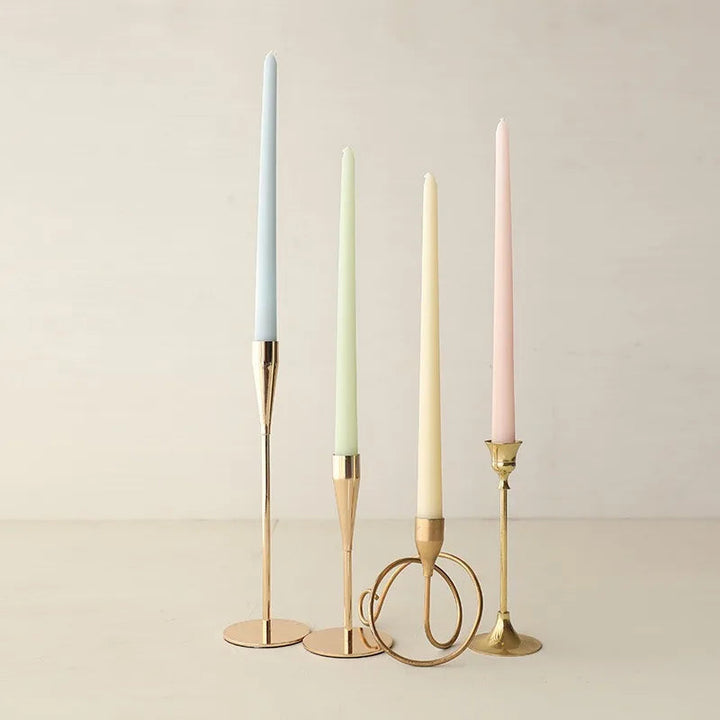 Pastel taper candles in gold holders, soft blue/green/cream/pink, minimalist table décor