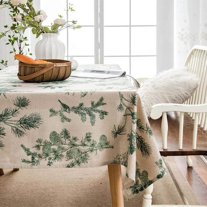 Dining room with a cotton tablecloth featuring green leaf patterns, a basket, and flowers.