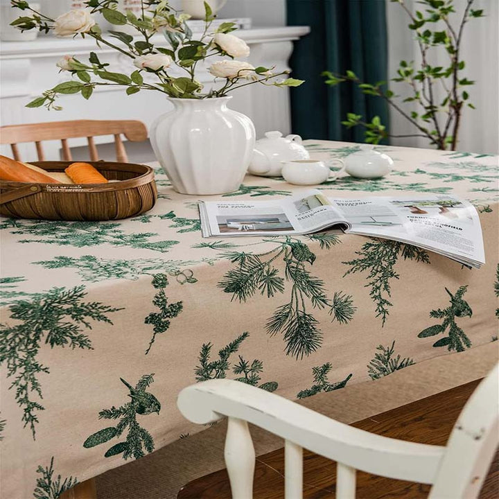 Dining table with a floral-patterned cotton tablecloth, white vase, and open magazine.