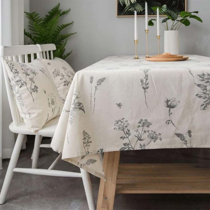 Dining room with a table covered by a floral-patterned cotton tablecloth, white chairs, and decorative elements.