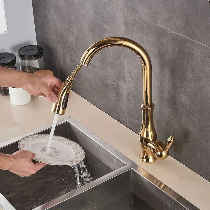 Gold kitchen tap with a plate being washed in a sink.