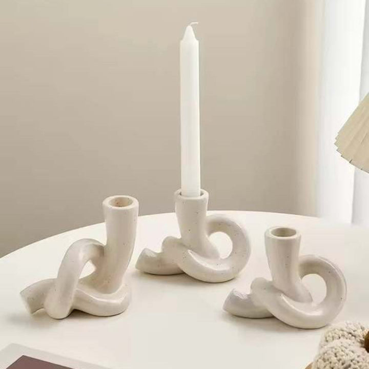 Set of three Nordic ceramic knot candle holders with taper candles on white table